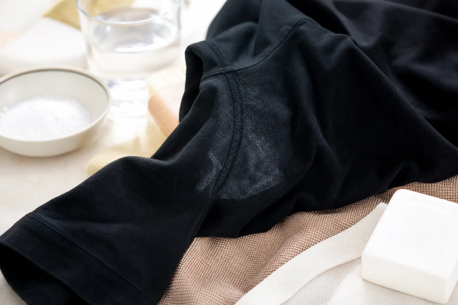 Gros plan sur un pull noir posé à plat, tissu en laine, lumière douce