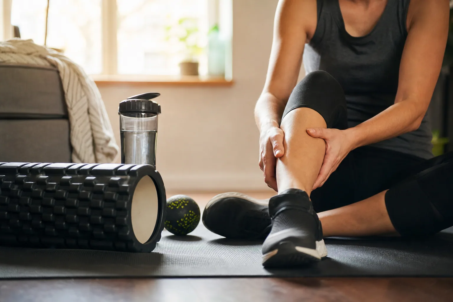 Personne s'étirant les jambes après une séance de sport en extérieur, lumière douce de fin de journée
