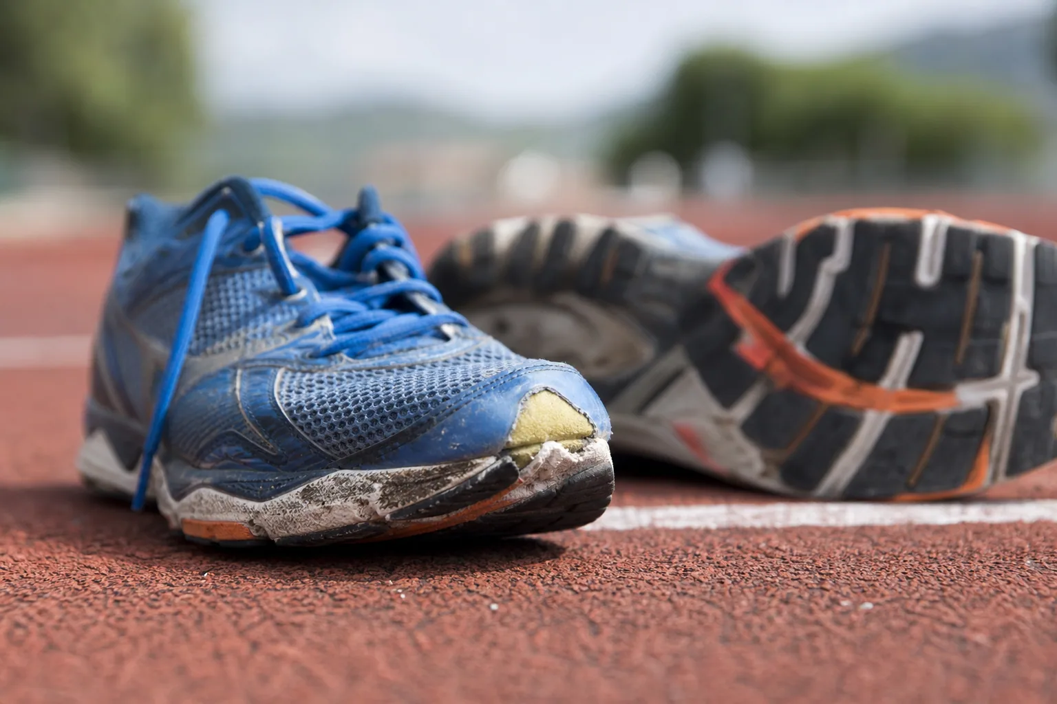 Paire de chaussures de running usées posée sur un sentier, gros plan sur la semelle